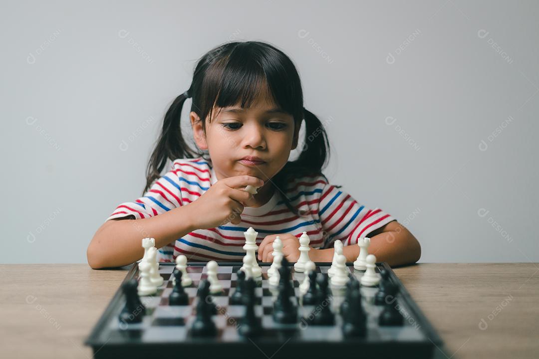 Menina asiática jogando xadrez em casa. um jogo de xadrez