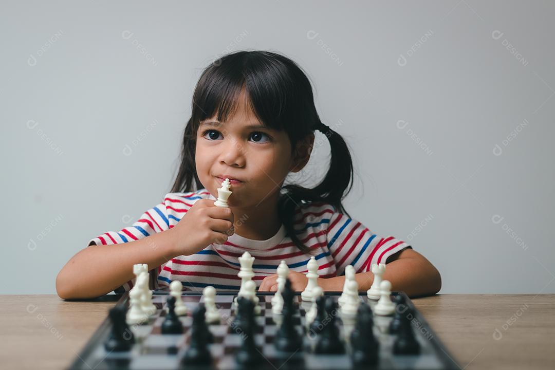 Menina asiática jogando xadrez em casa. um jogo de xadrez