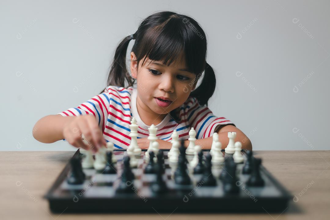Menina asiática jogando xadrez em casa. um jogo de xadrez