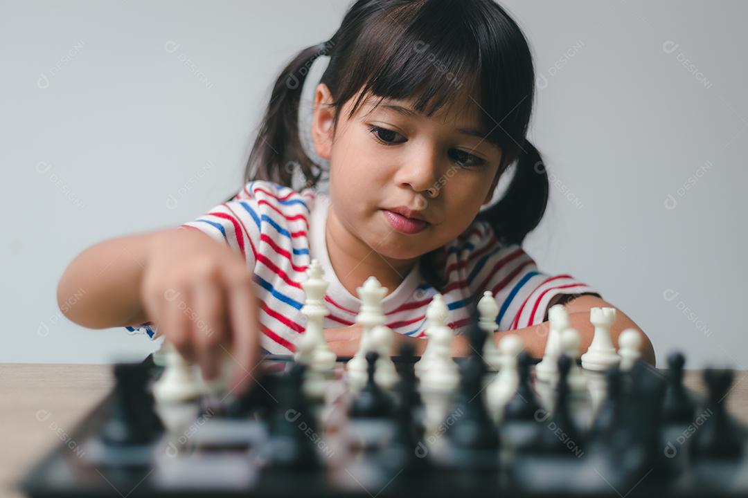 Menina asiática jogando xadrez em casa. um jogo de xadrez