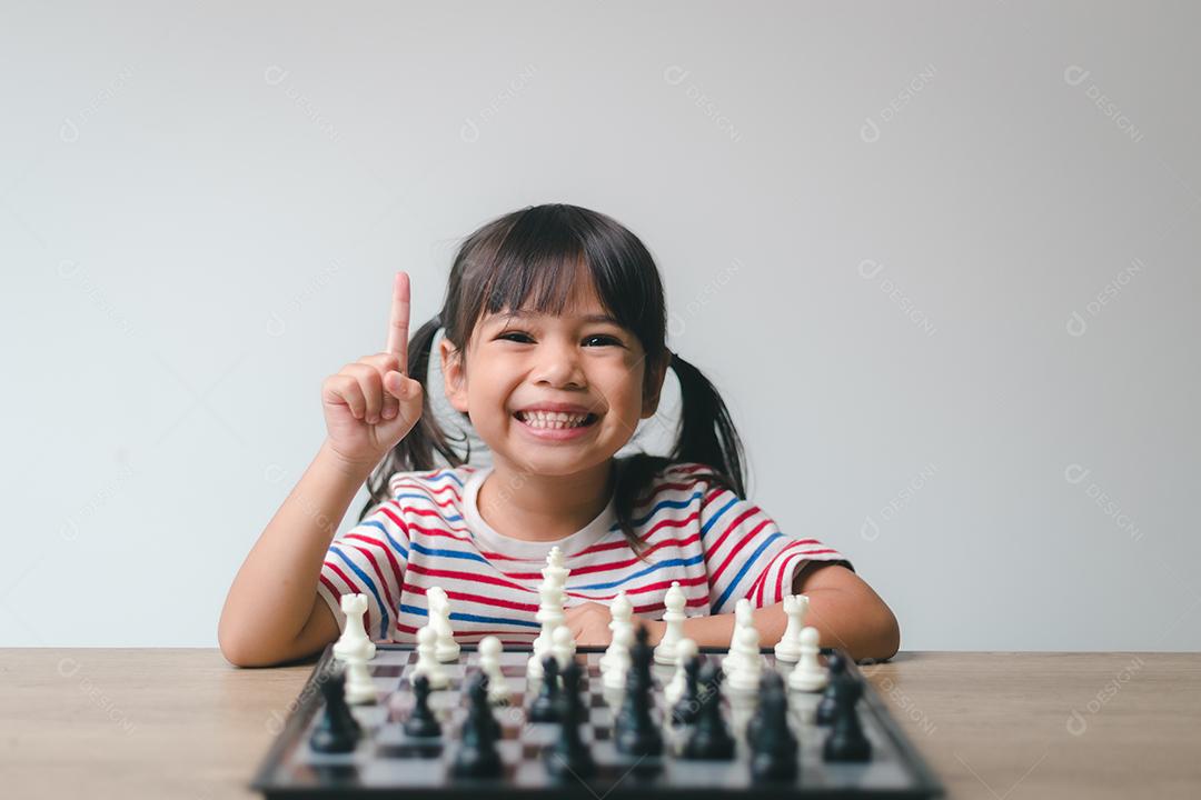 Menina asiática jogando xadrez em casa. um jogo de xadrez