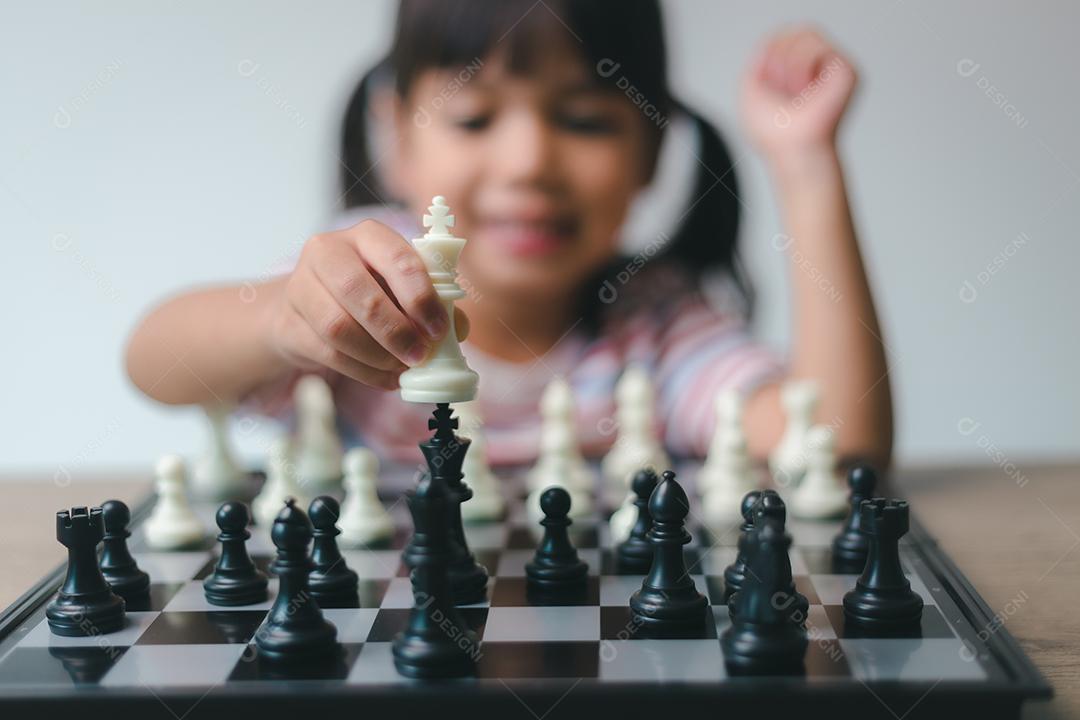 Menina asiática jogando xadrez em casa. um jogo de xadrez