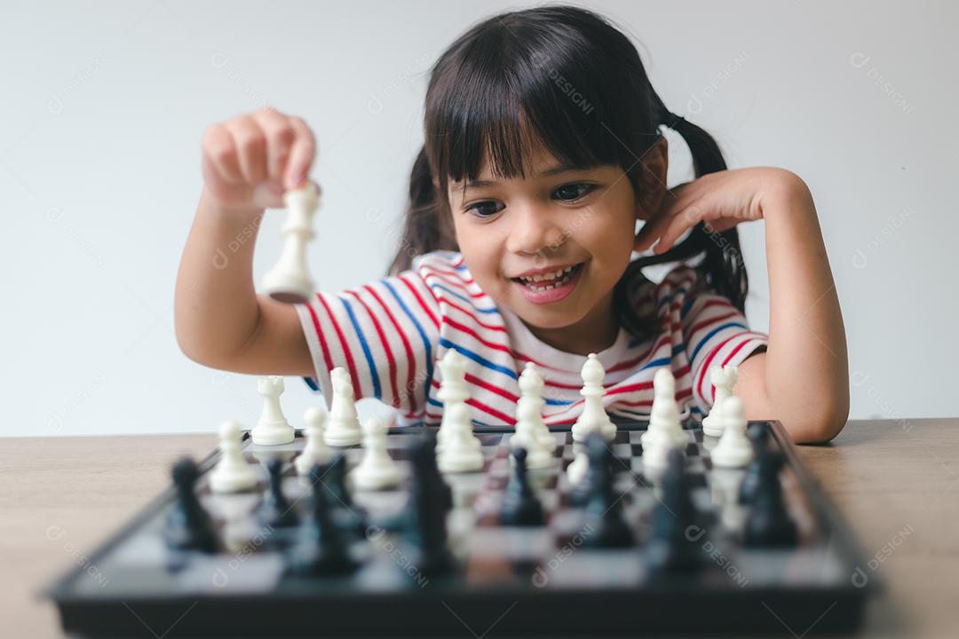 Menina asiática jogando xadrez em casa. um jogo de xadrez