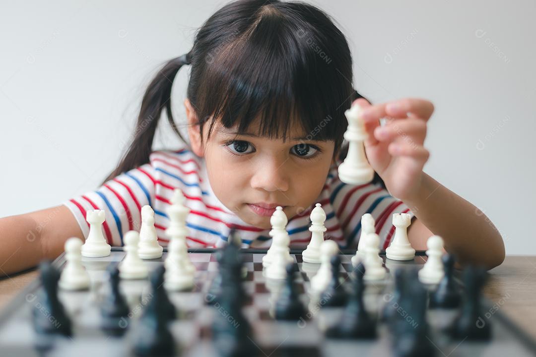 Menina asiática jogando xadrez em casa. um jogo de xadrez