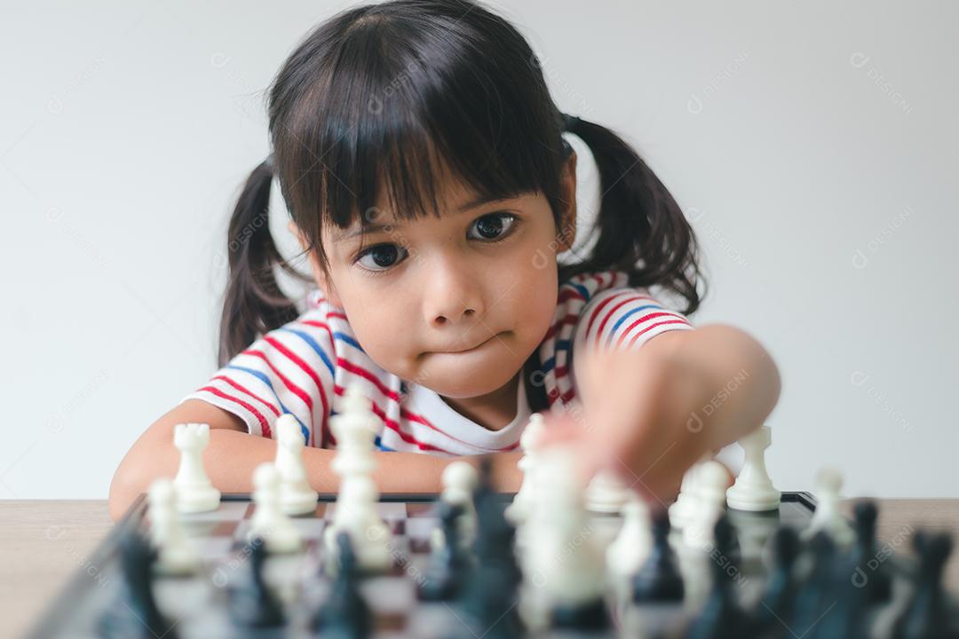 Menina asiática jogando xadrez em casa. um jogo de xadrez