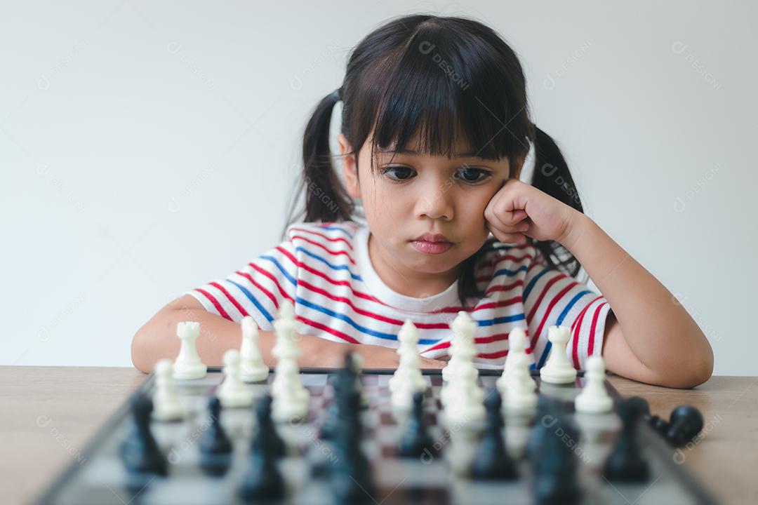 Menina asiática jogando xadrez em casa. um jogo de xadrez