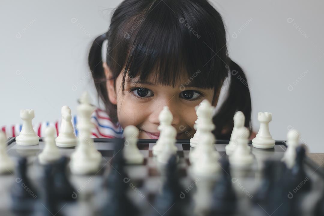 Menina asiática jogando xadrez em casa. um jogo de xadrez