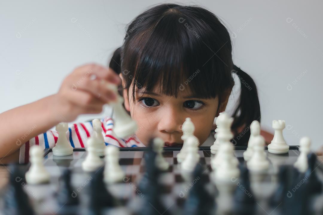 Menina asiática jogando xadrez em casa. um jogo de xadrez