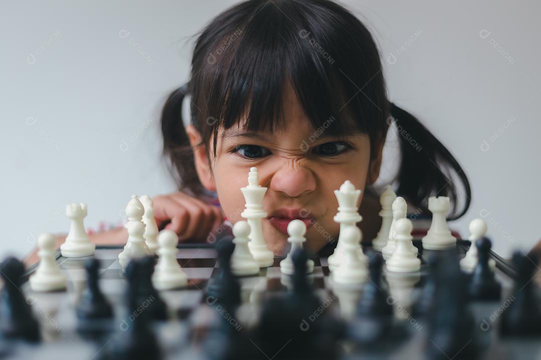 Menina asiática jogando xadrez em casa. um jogo de xadrez