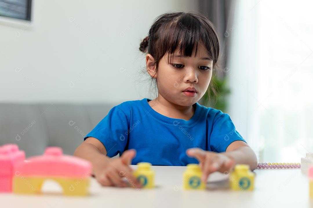 Menina asiática jogando blocos de brinquedo criativos para educação em casa