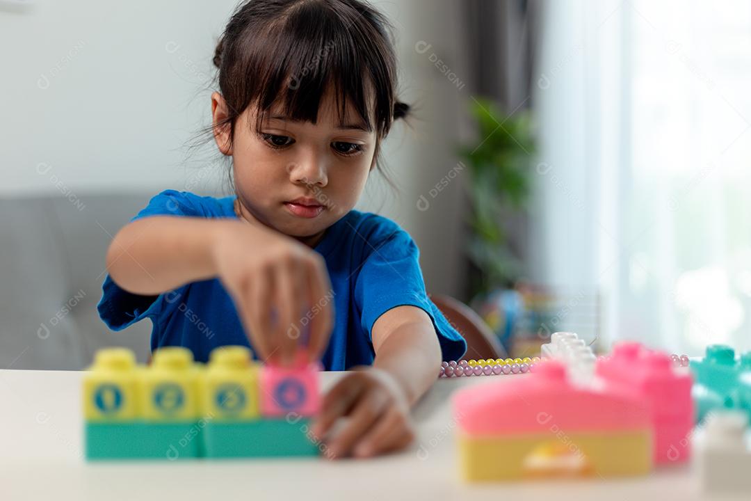 Menina asiática jogando blocos de brinquedo criativos para educação em casa