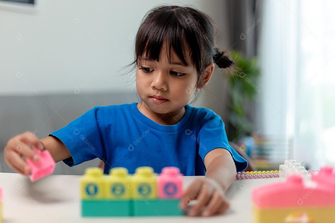 Menina asiática jogando blocos de brinquedo criativos para educação em casa