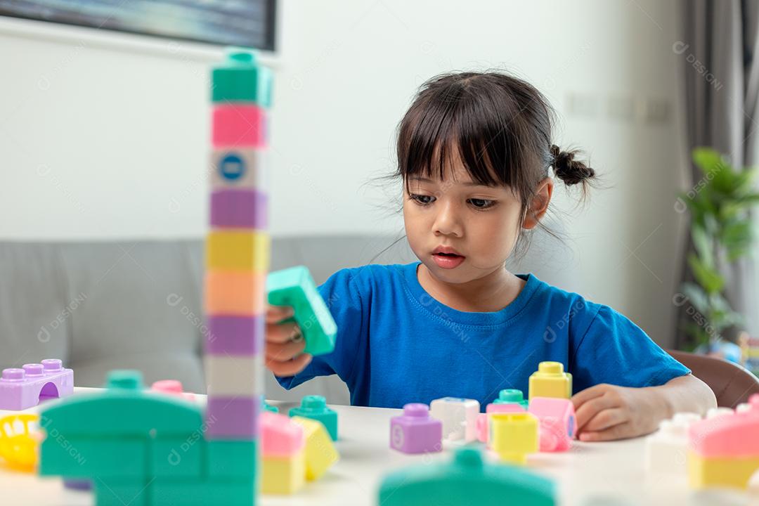 Menina asiática jogando blocos de brinquedo criativos para educação em casa