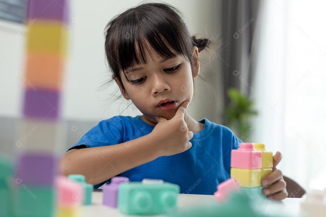 Menina asiática jogando blocos de brinquedo criativos para educação em casa