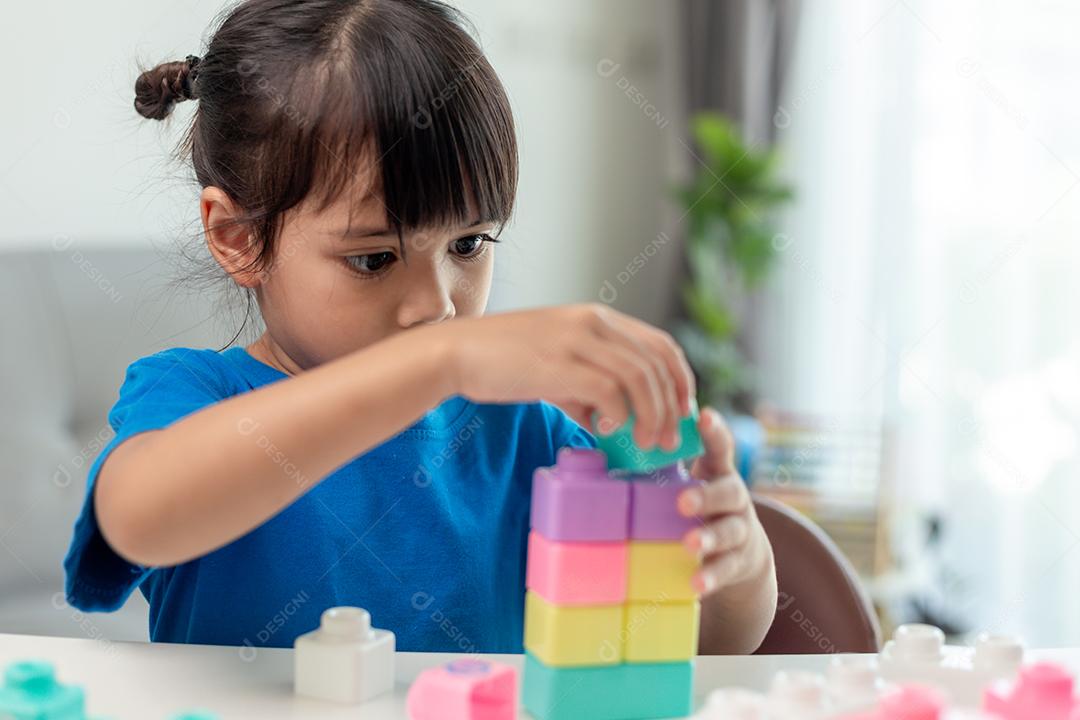 Menina asiática jogando blocos de brinquedo criativos para educação em casa