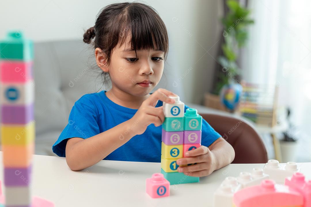 Menina asiática jogando blocos de brinquedo criativos para educação em casa