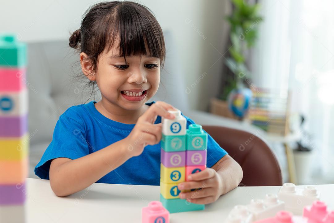 Menina asiática jogando blocos de brinquedo criativos para educação em casa