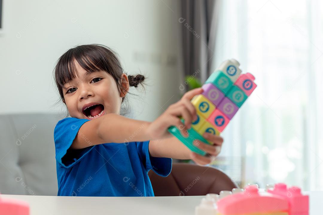 Menina asiática jogando blocos de brinquedo criativos para educação em casa