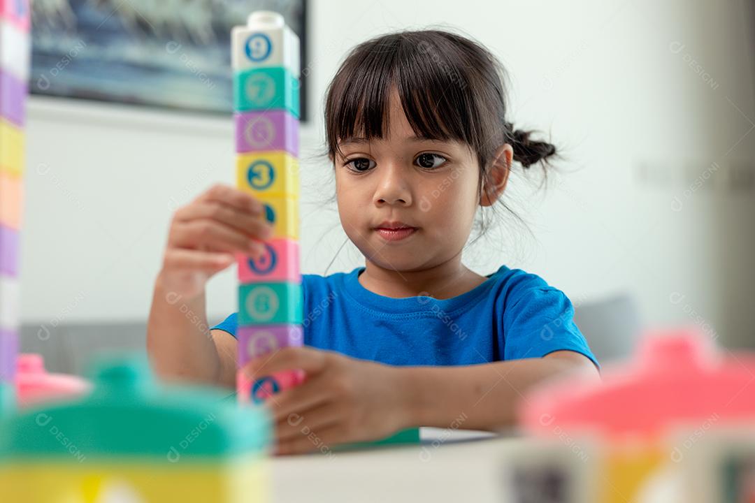 Menina asiática jogando blocos de brinquedo criativos para educação em casa