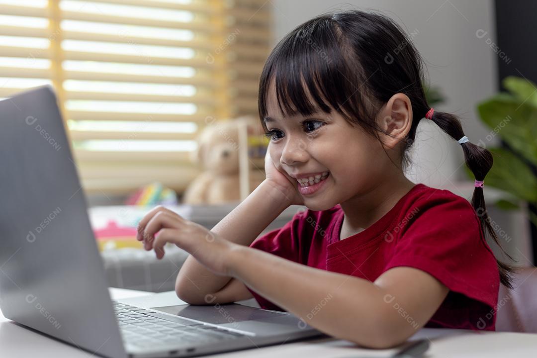 Menina asiática usando computador portátil para estudo on-line em casa durante a quarentena em casa. ensino em casa, estudo on-line, quarentena em casa, aprendizado on-line, vírus corona ou conceito de tecnologia educacional