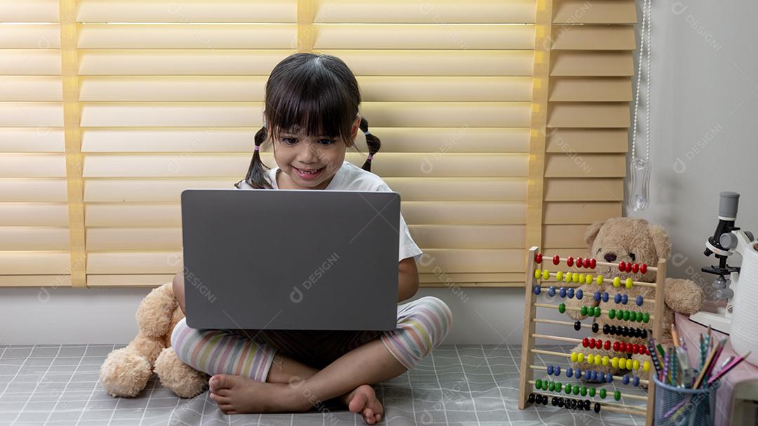 Menina asiática usando computador portátil para estudo on-line em casa durante a quarentena em casa. ensino em casa, estudo on-line, quarentena em casa, aprendizado on-line, vírus corona ou conceito de tecnologia educacional
