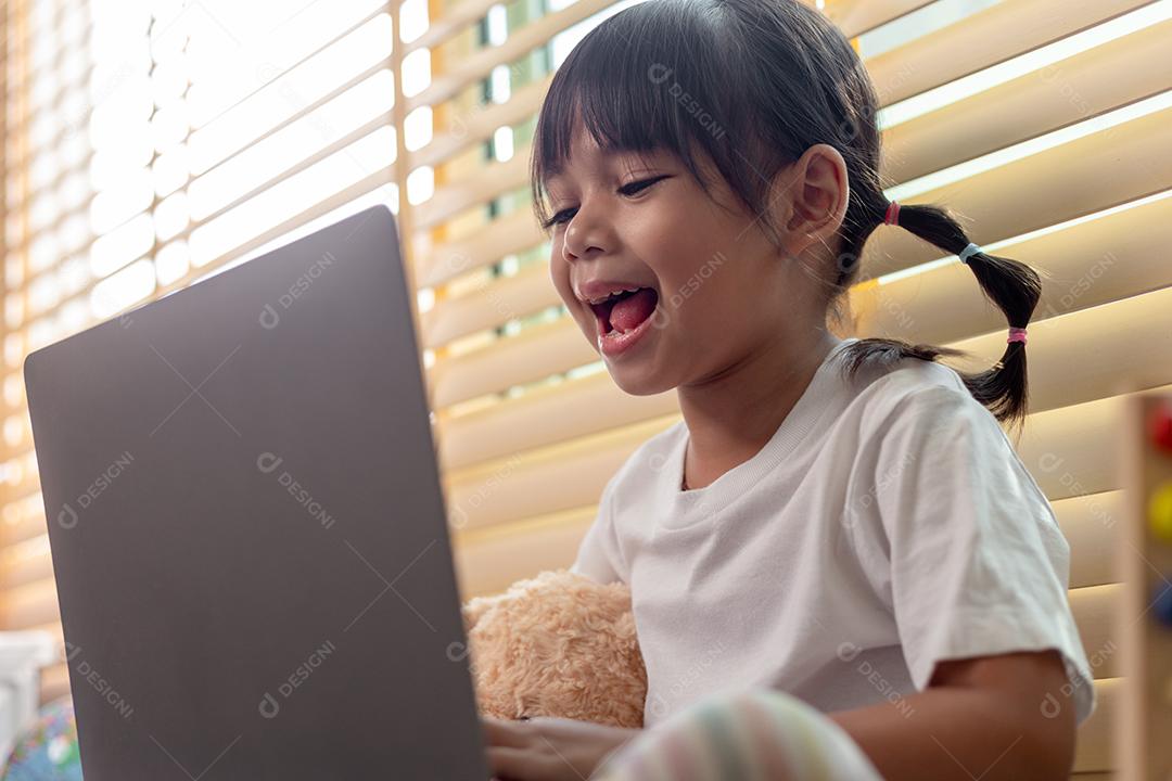 Menina asiática usando computador portátil para estudo on-line em casa durante a quarentena em casa. ensino em casa, estudo on-line, quarentena em casa, aprendizado on-line, vírus corona ou conceito de tecnologia educacional