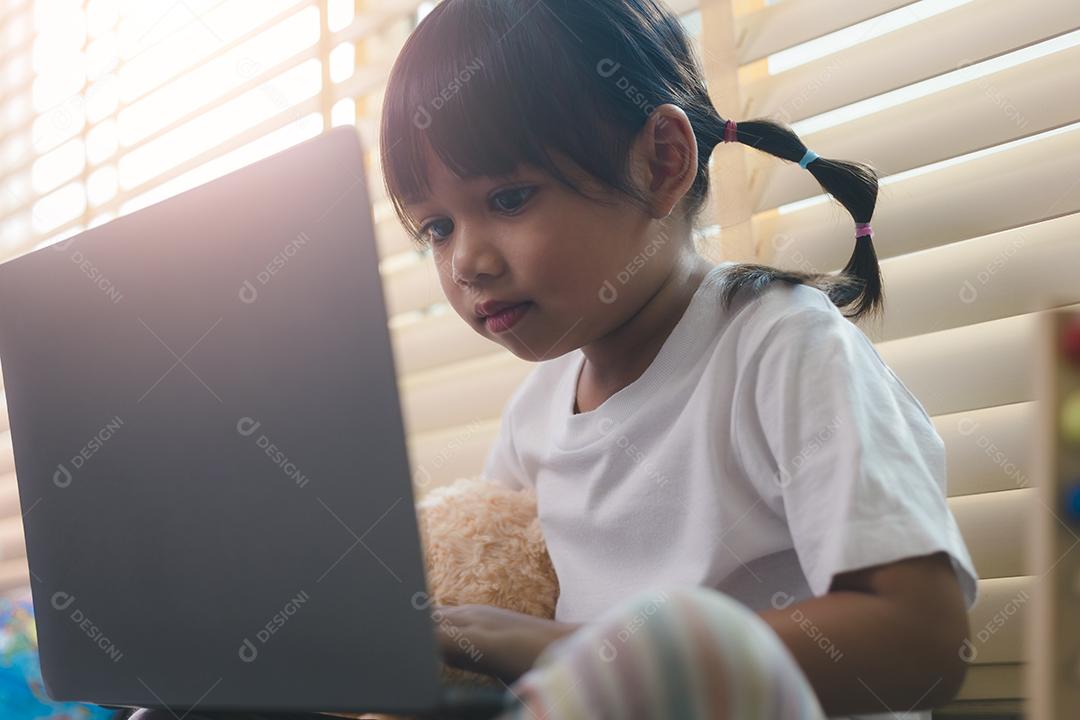 Menina asiática usando computador portátil para estudo on-line em casa durante a quarentena em casa. ensino em casa, estudo on-line, quarentena em casa, aprendizado on-line, vírus corona ou conceito de tecnologia educacional