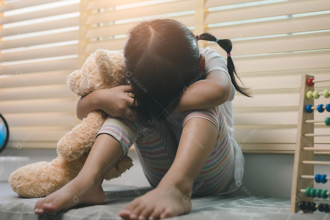 Feche a garotinha solitária abraçando o brinquedo, sentada em casa sozinha, chateada criança infeliz esperando pelos pais, pensando em problemas, relacionamento ruim na família, trauma psicológico