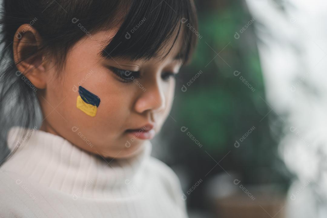 Uma criança com a bandeira da Ucrânia está chorando. Tristeza desejando esperança. As lágrimas das crianças da guerra. Evacuação de civis. Liberdade para a Ucrânia
