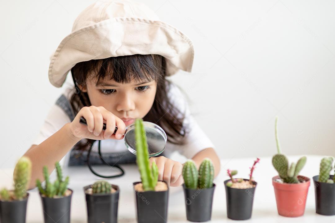 garoto toca suavemente o novo caule do cacto que ele cresce com cuidado, uma mão segura lupa. Educação da natureza, Montessori e conceito de habilidades de observação.