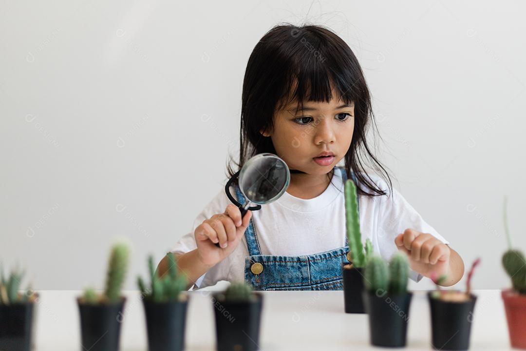 garoto toca suavemente o novo caule do cacto que ele cresce com cuidado, uma mão segura lupa. Educação da natureza, Montessori e conceito de habilidades de observação.