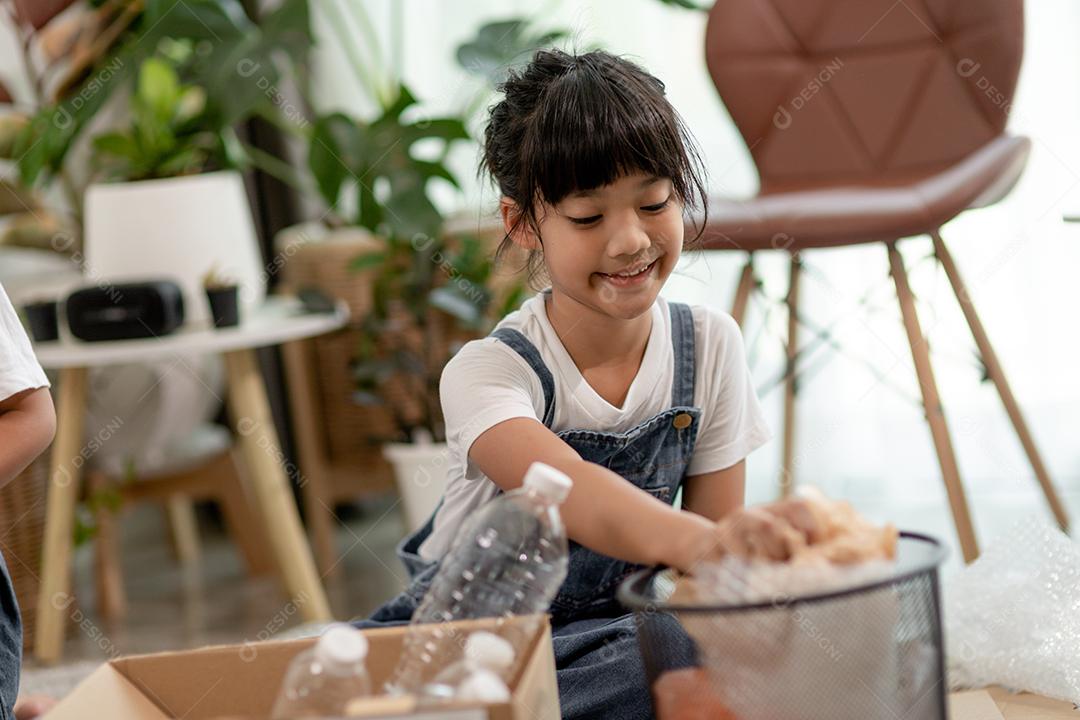 Crianças sorridentes se divertindo enquanto segregavam garrafas plásticas e papel em uma lixeira