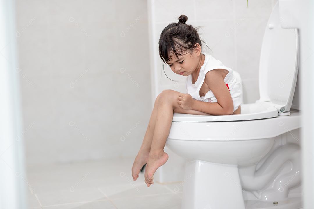 A garotinha está sentada no vaso sanitário sofrendo de constipação ou hemorroida.