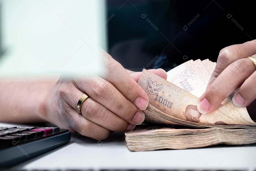 mão de um funcionário do banco masculino contando grandes somas de dinheiro para fornecer serviços financeiros aos consumidores. Há uma calculadora ao lado para facilitar o trabalho, investimento, contagem, comércio de gráficos digitais