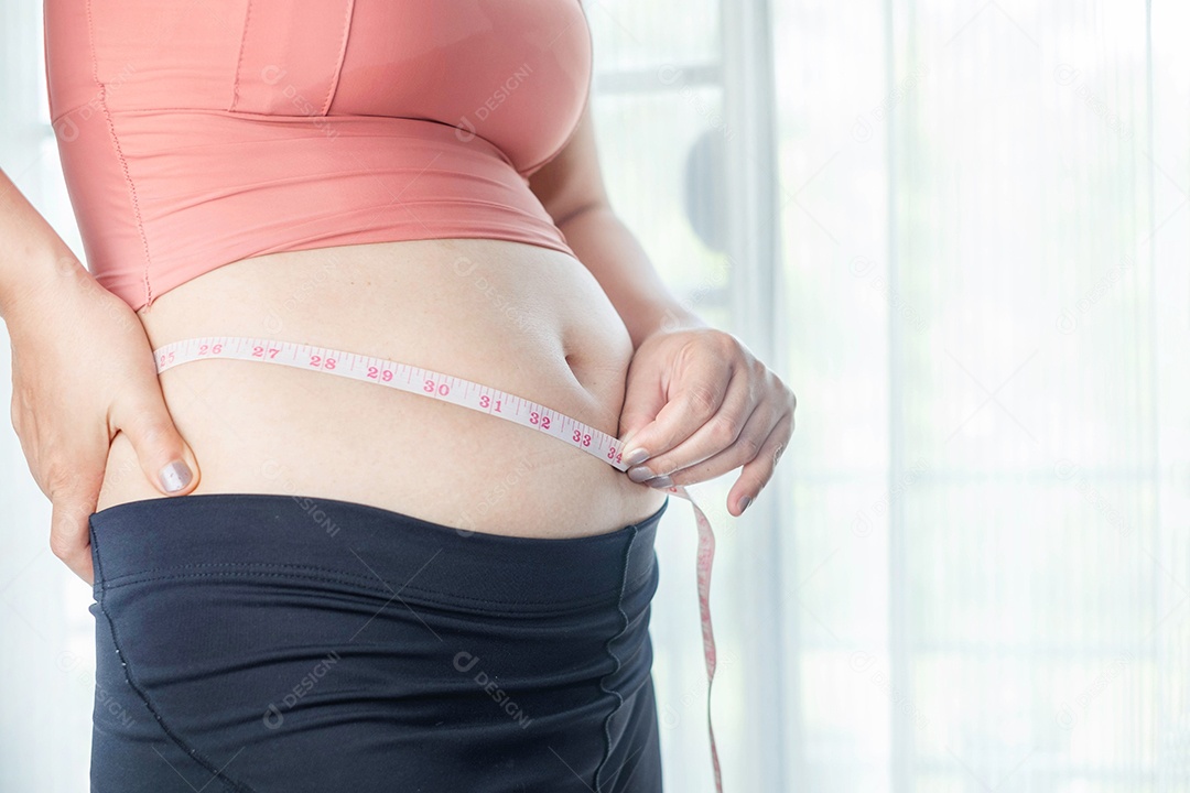 Conceito de cuidados com o corpo: a mão da mulher beliscando o excesso de gordura da barriga, corpo de mulher gorda e insalubre