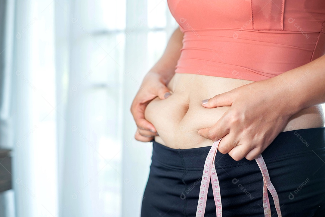 Conceito de cuidados com o corpo: a mão da mulher beliscando o excesso de gordura da barriga, corpo de mulher gorda e insalubre