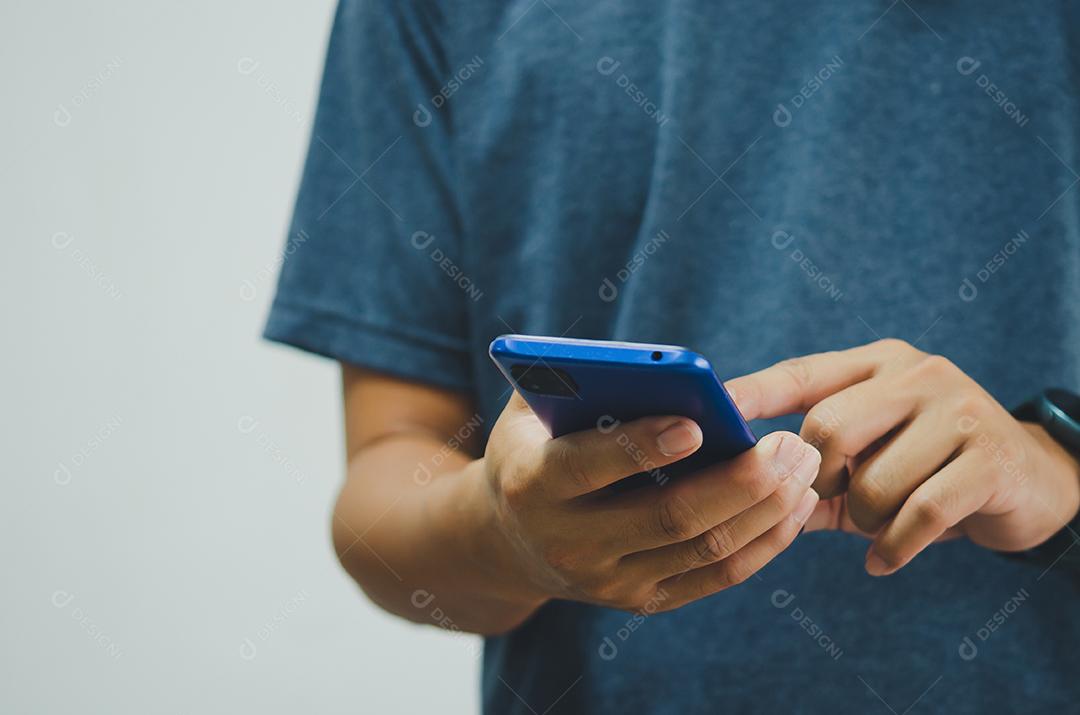 Homem de camisa azul está pressionando um telefone celular no fundo.
