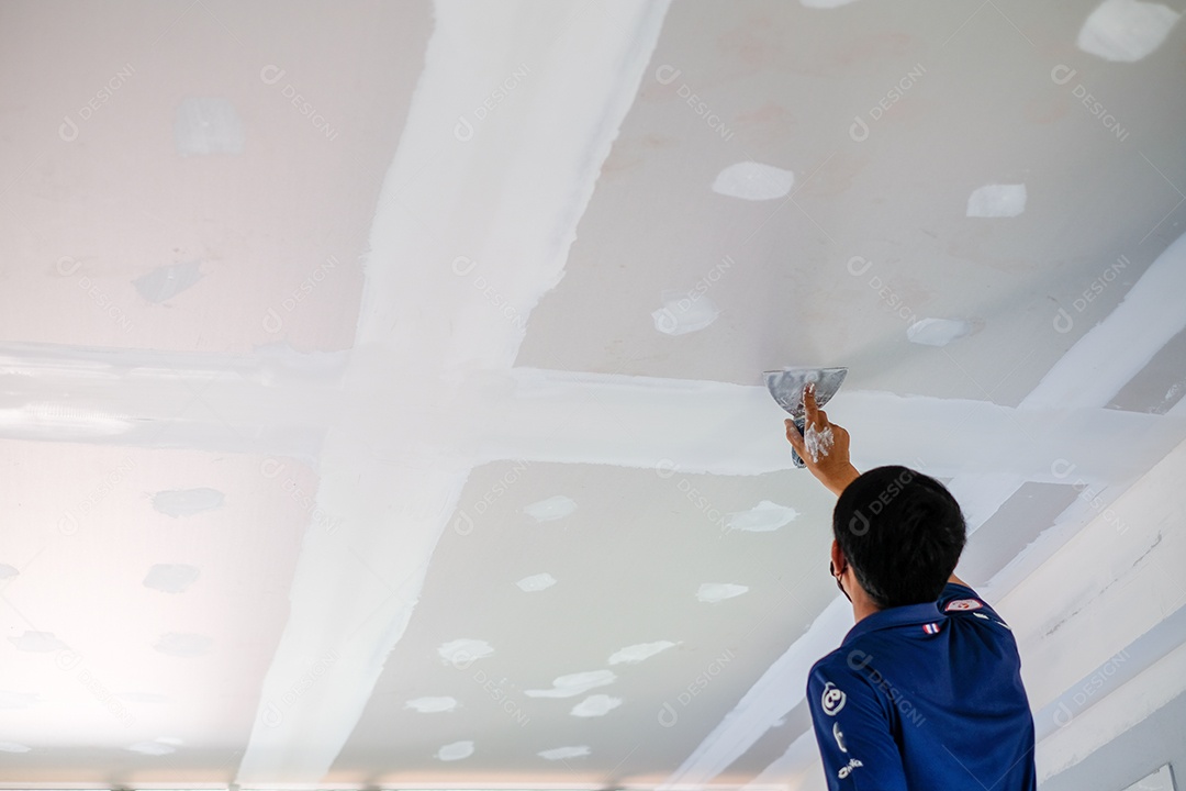 Artesão masculino está usando uma lanterna branca para fazer tetos na casa, construir uma casa, decorar o interior da casa.