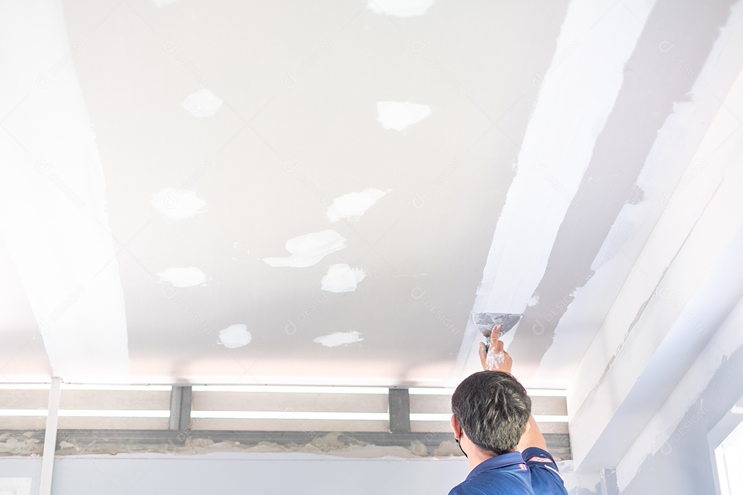 Artesão masculino está usando uma lanterna branca para fazer tetos na casa, construir uma casa, decorar o interior da casa.