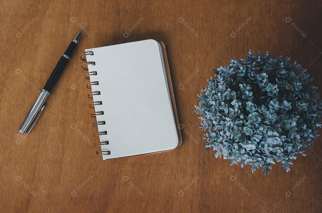 Caderno em branco e caneta e flor na mesa de madeira vintage