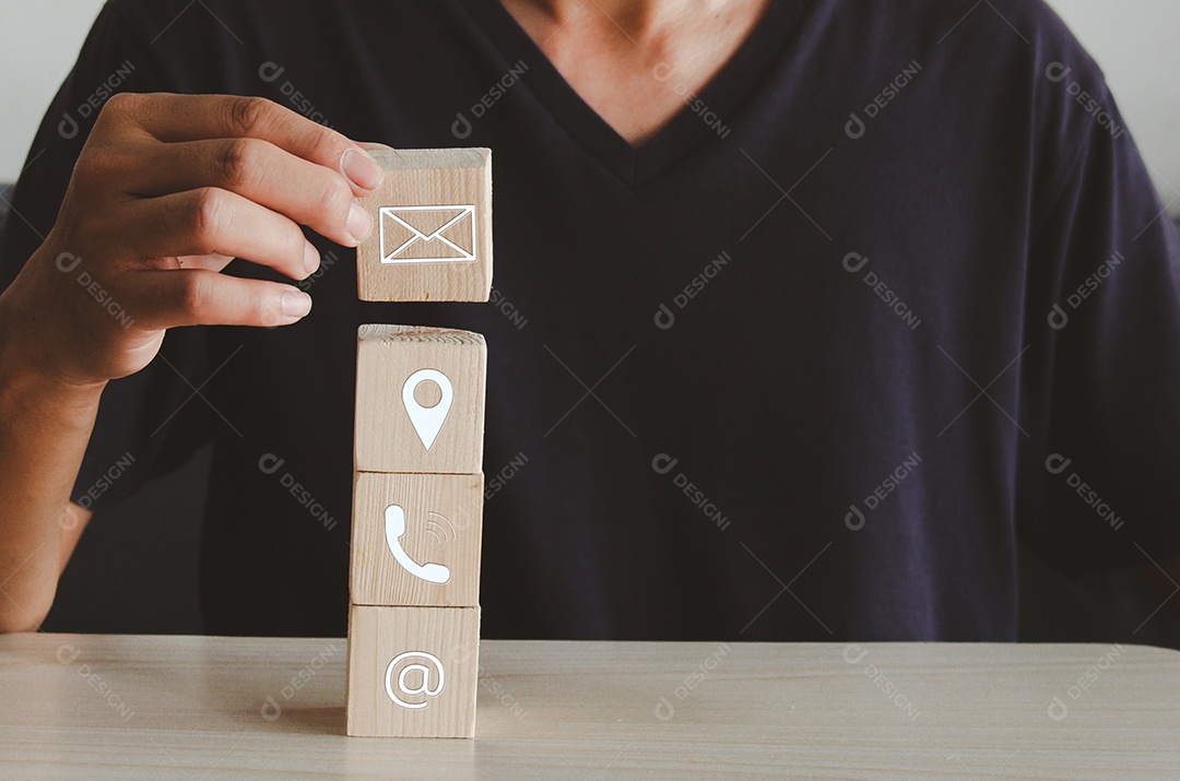 Mão segurando a localização do telefone da letra do ícone do bloco do cubo de madeira e o endereço na mesa. Comunicação empresarial e conceito de rede social.