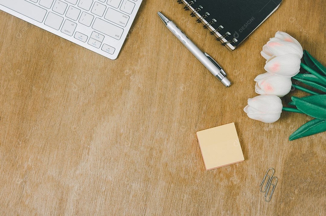 Caderno plano de vista superior e flor e caneta com teclado de computador na mesa de madeira