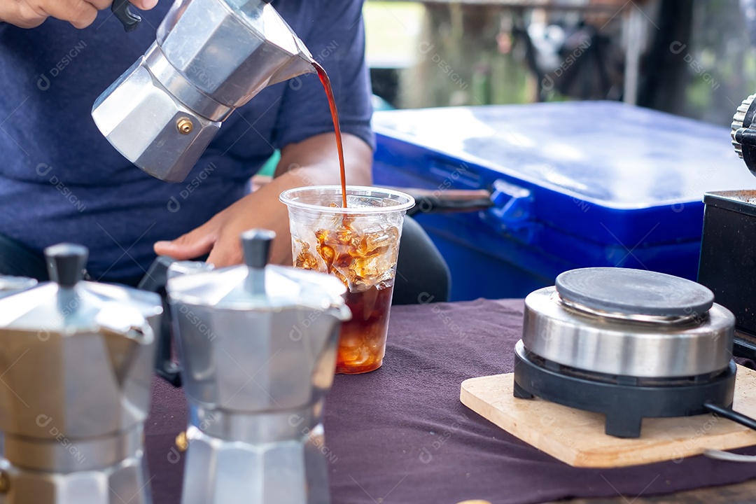 homem derramando café da cafeteira moka para uma xícara de café. Mão segurando o pote de moka clássico italiano derramando café, estilo vintage de café