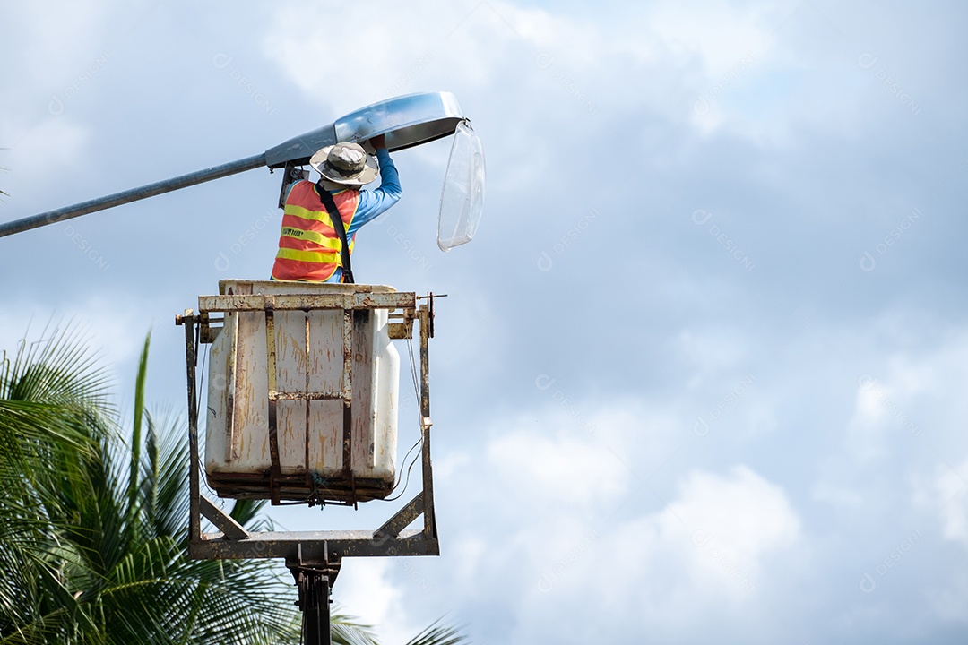 Trabalhador do sexo masculino sentado em um teleférico para acender uma lâmpada de rua, segurança no trabalho.