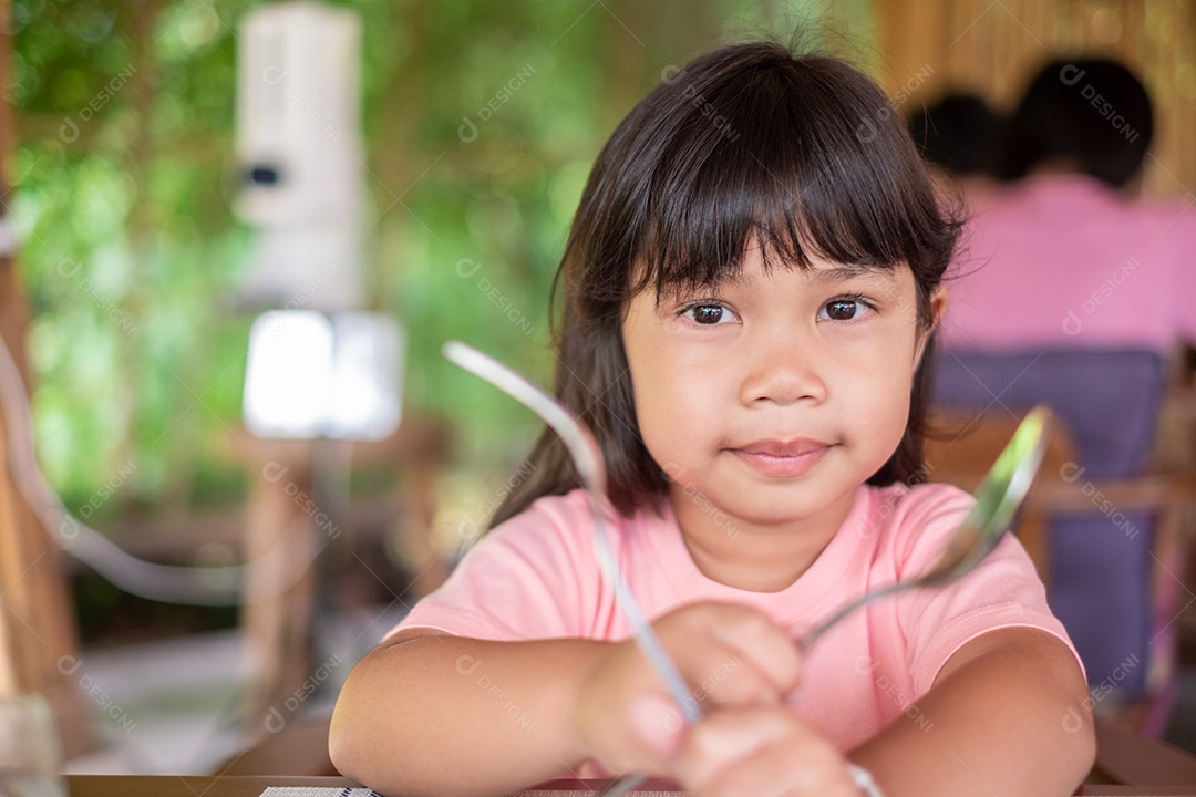 Linda garota asiática vestindo uma camisa rosa. segurando uma colher de reparo para se preparar para o café da manhã