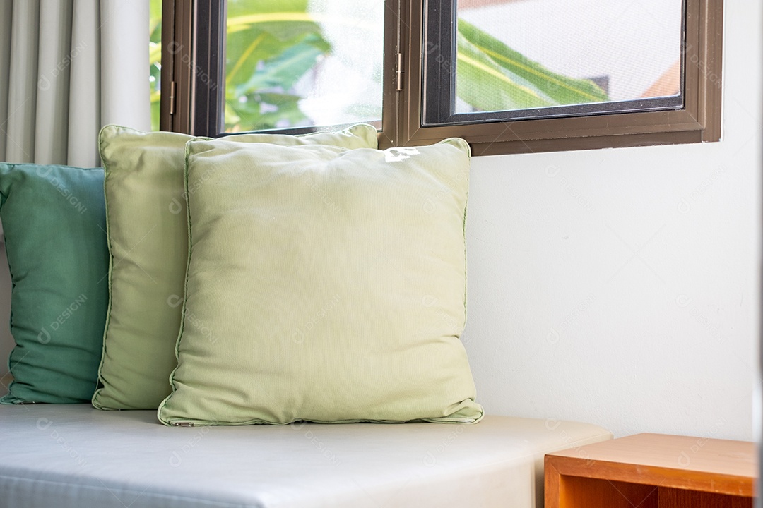Sofá com almofadas perto das janelas na sala de estar