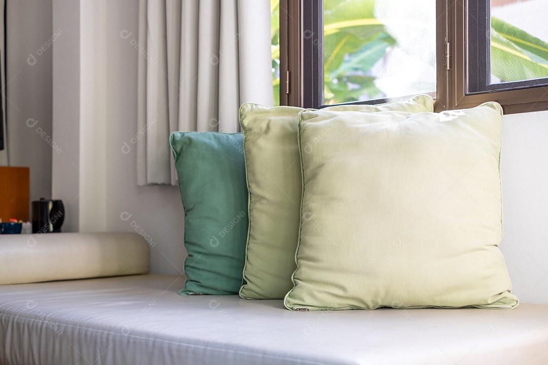 Sofá com almofadas perto das janelas na sala de estar