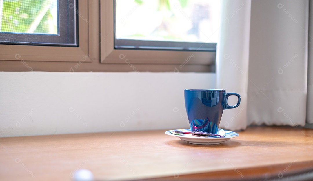 Caneca de café azul é colocada ao lado da janela pela manhã, tempo de relaxamento, fresco fraco