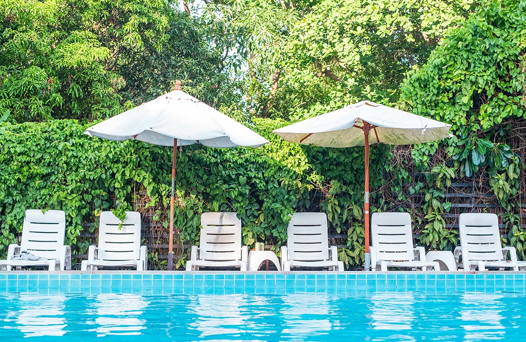 Espreguiçadeiras e guarda-sóis de praia perto da piscina no resort e fundo verde da natureza