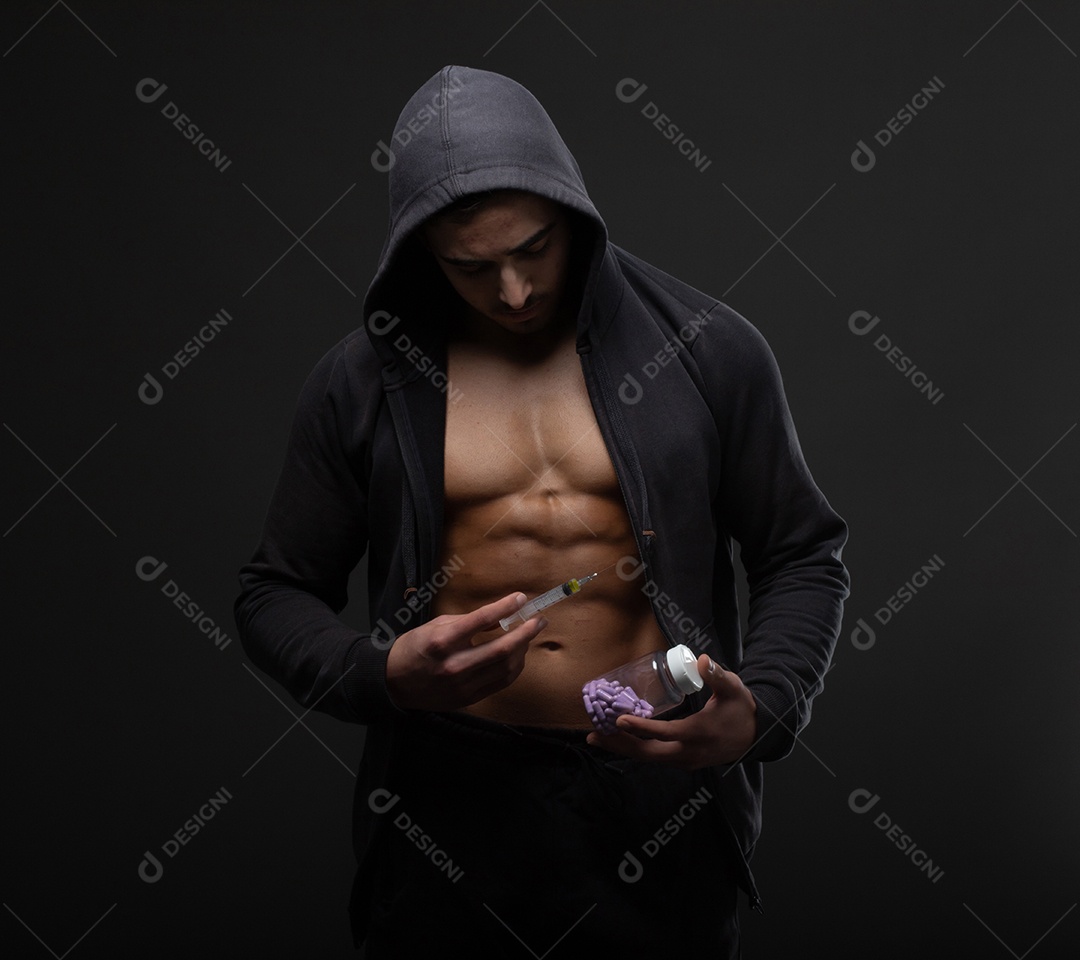 Homem musculoso com uma seringa na mão. Usuário de esteroides anabolizantes para treinamento de força